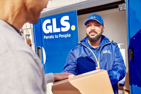 GLS Zustellfahrer stellt ein Paket beim Kunden zu