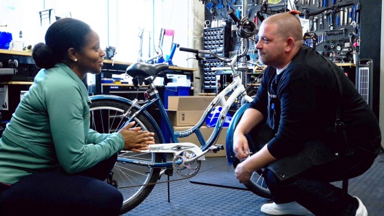 A man and woman talking to each other in a bike shop.