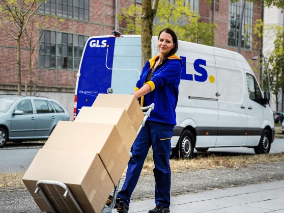 GLS female driver delivering parcels in a city setting.