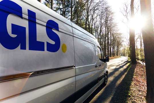 GLS parcel van driving through a forest.