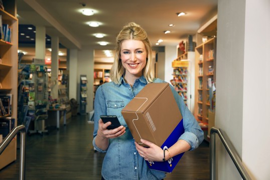 Smiling blond woman holding a parcel in a store.