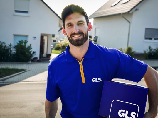 GLS delivery driver with a parcel on a street