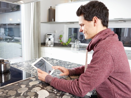 GLS zákazník ve své kuchyni pomocí svého tabletu ke sledování jeho zásilky