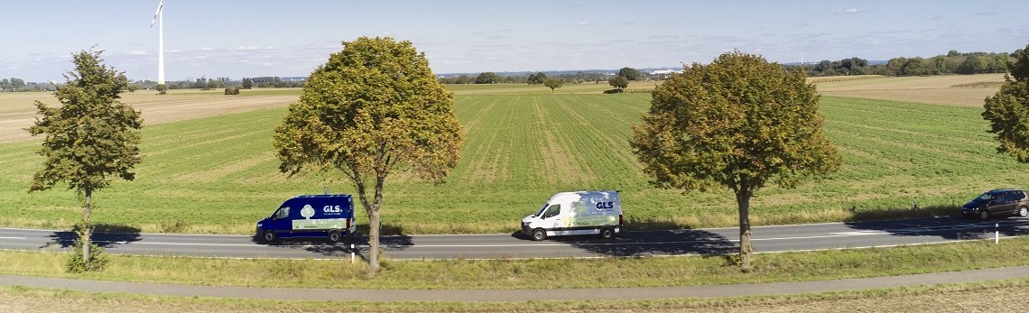 Two GLS delivery vehicles driving on a country road