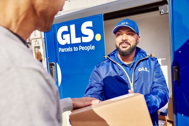Repartidor de paquetería entregando un paquete a cliente en punto de recogida GLS junto a taquilla automática de envíos