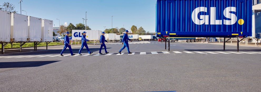 GLS employees walking outside depot on crosswalk and there is a blue color GLS swap body behind them.