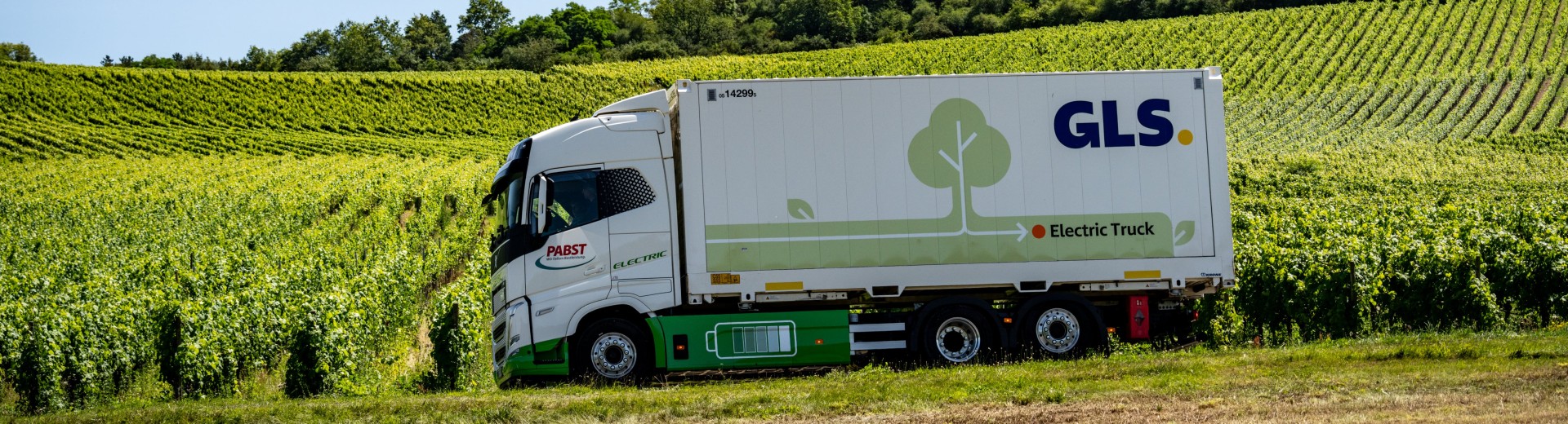GLS electric truck driving through vineyards, highlighting the company’s commitment to sustainable and net-zero emission transport.