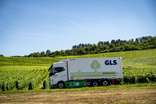 GLS electric truck driving through vineyards, highlighting the company’s commitment to sustainable and net-zero emission transport.