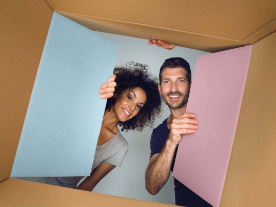 A woman and a man look at a cardboard box from below