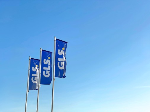 Blue GLS flags fluttering in the wind against a clear blue sky.