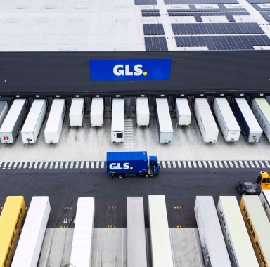 Aerial view of GLS Paris logistics hub with solar-panel roof and trucks at loading bays.