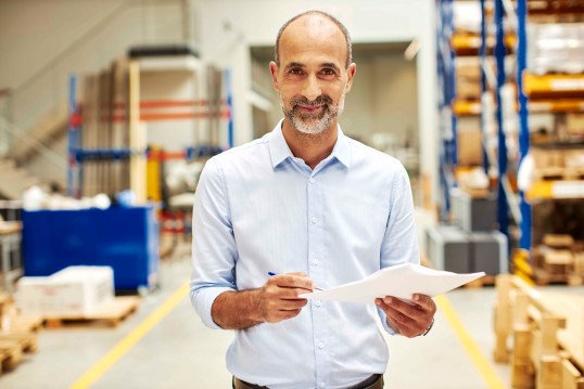 Middle aged man holding documents in a warehouse
