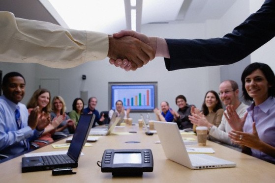 shaking hands in front of a GLS employee sitting at a conference table.