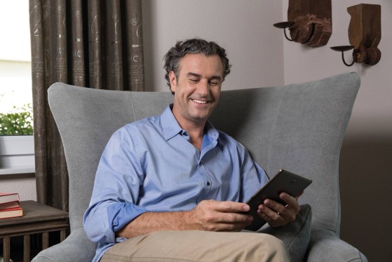 GLS customer sitting on a sofa in living room, using his smartphone