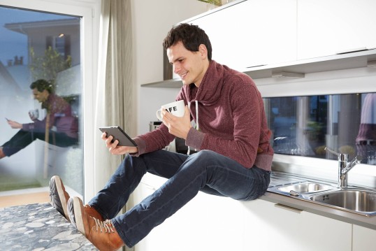 GLS deliver van out for deliveries; Customer uses his phone to change his delivery while sitting on a counter