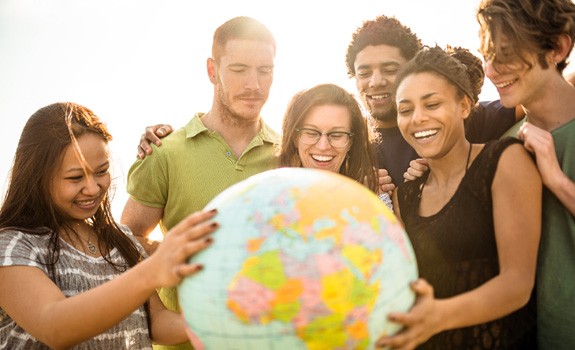 Multi-ethnic group of people observes a globe