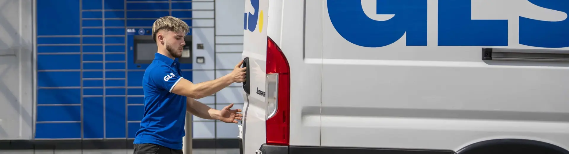 GLS courier handling parcels with a GLS van in the background