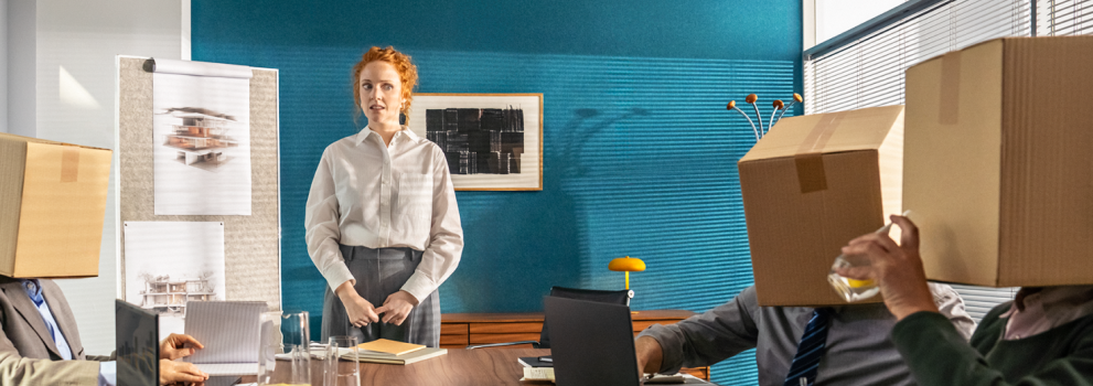 Confused woman in front of a desk with parcels instead of colleagues.