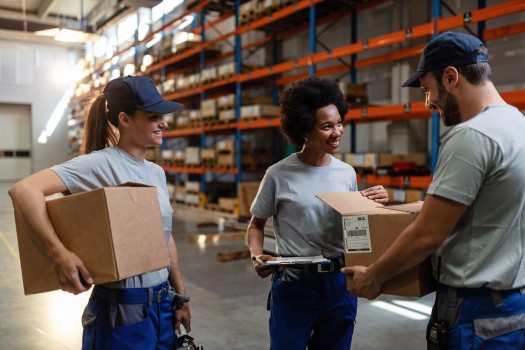 Workers handling boxes and discussing tasks in a warehouse.
